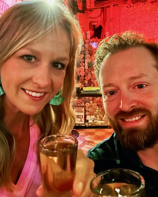 A woman and a man cheersing with tequila shots